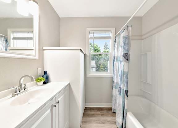 A white bathroom with a window and a white tub. at River Lofts Apartments, Oregon, 97062