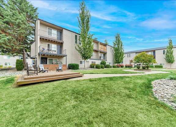 A sunny day at a well-kept apartment complex with a green lawn and trees. at River Lofts Apartments, Tualatin, Oregon