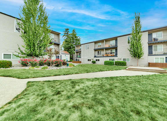 A sunny day at a residential area with apartment buildings and green lawns. at River Lofts Apartments, Tualatin
