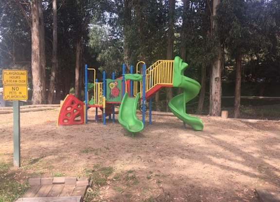 A playground with a green slide and a red and yellow structure at Salinas Sunset Apartments, Salinas, 93907