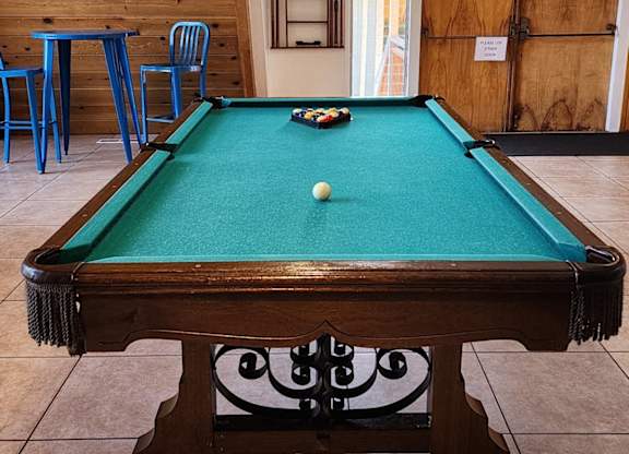A pool table with a green cloth and a white ball in the middle. at Salinas Sunset Apartments, Salinas, CA