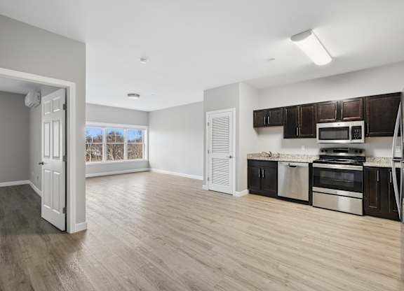 A kitchen with a white door and a microwave above the stove.