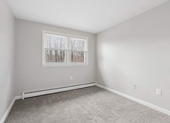 A bedroom with a window and carpeted floor.