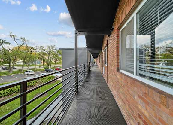 A balcony with a black railing and a brick wall.