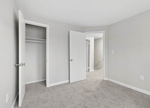 A bedroom with a carpeted floor and a closet.