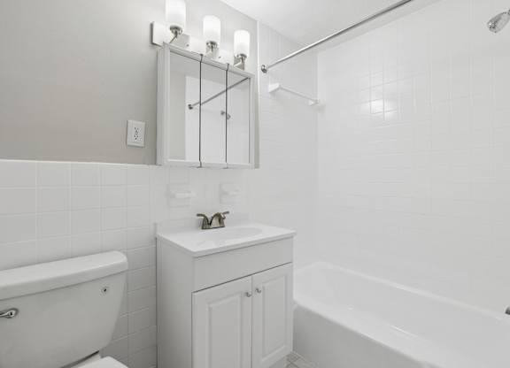 A white bathroom with a tub, sink, and mirror.