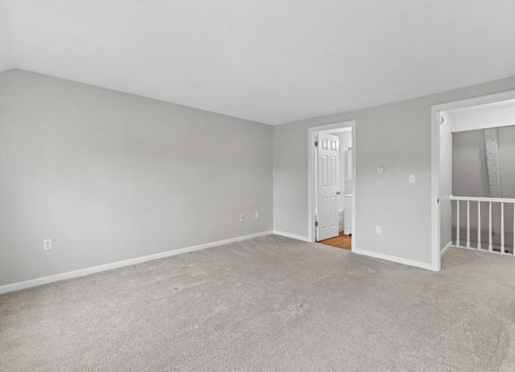 A spacious room with a carpeted floor and white walls.