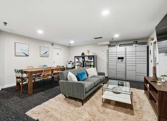 A living room with a grey couch, a wooden table, and a rug.