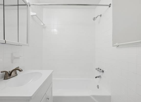 A white bathroom with a sink and bathtub.