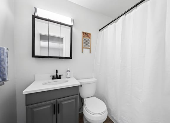 A white bathroom with a toilet, sink, and shower curtain.