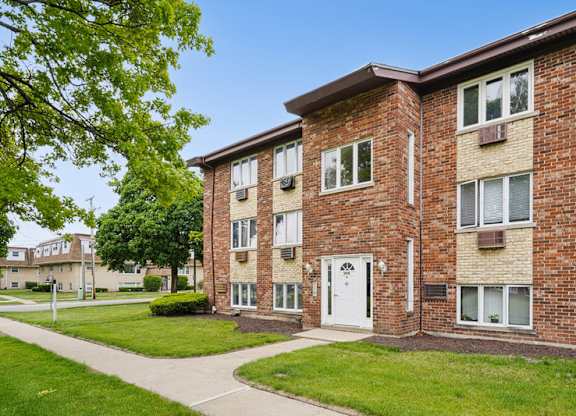 A brick apartment building with a white door and windows.