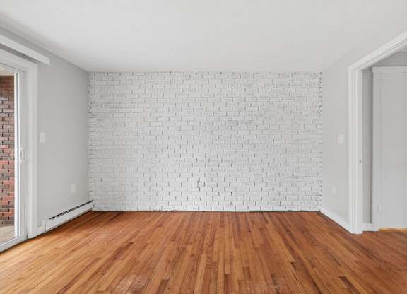 A room with a white brick wall and wooden flooring.
