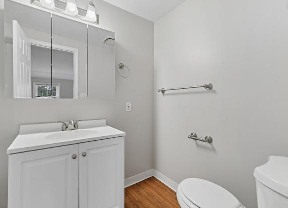 A white bathroom with a toilet, sink, and mirror.