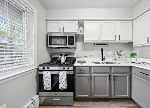 A kitchen with a stove, microwave, and cabinets.