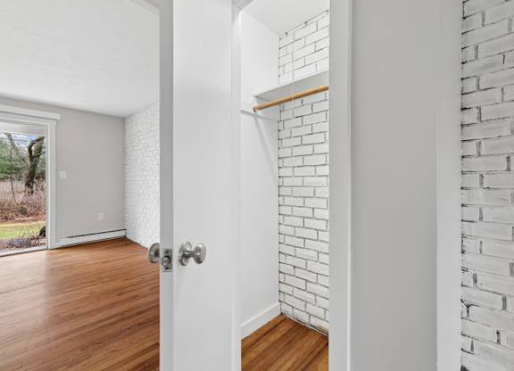 A white door with a silver handle is in a room with a white brick wall.