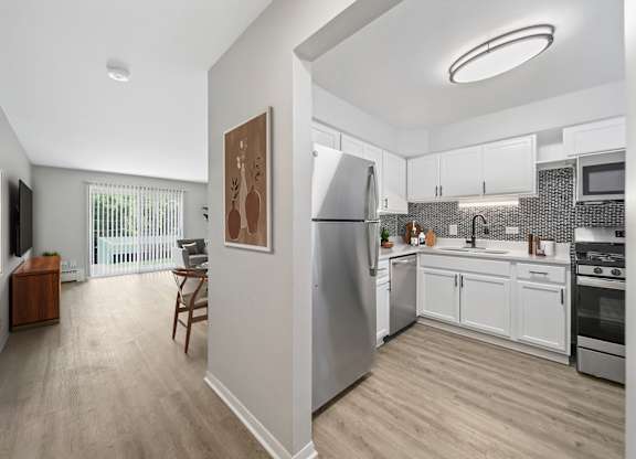 A modern kitchen with stainless steel appliances and wooden flooring.
