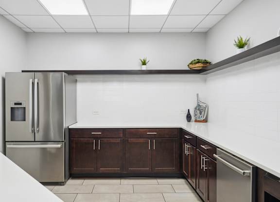 A kitchen with a stainless steel refrigerator and wooden cabinets.