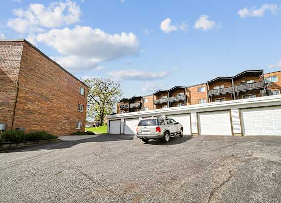 A silver car is parked in front of a two-story apartment building.