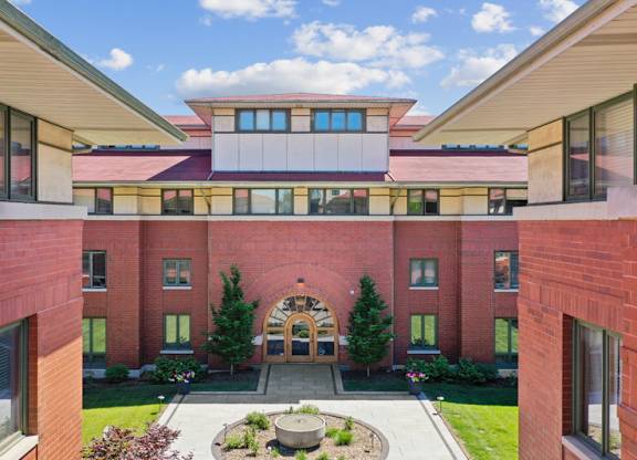 A red brick building with a circular entrance and a courtyard in front.