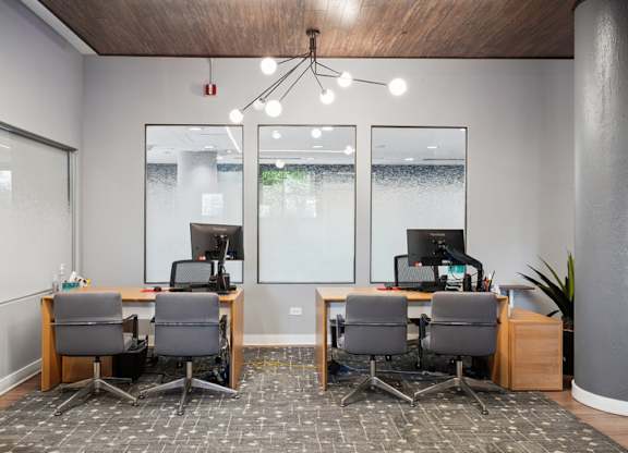 Two desks with computers and chairs in a room.