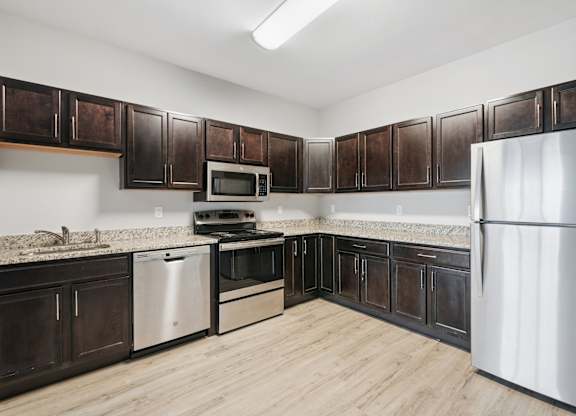 A kitchen with dark brown cabinets and stainless steel appliances.