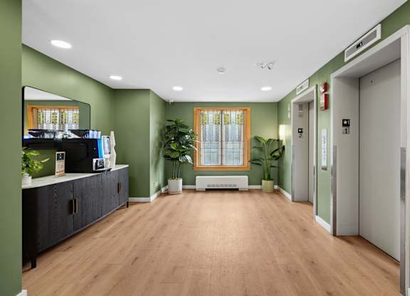 A hallway with a green wall and a wooden floor.