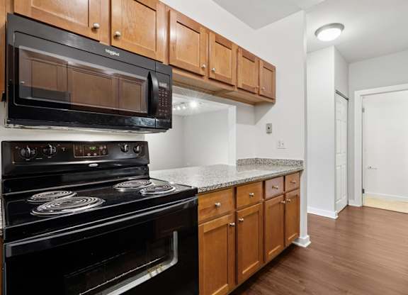 A black microwave oven is mounted above a black stove with a silver handle.