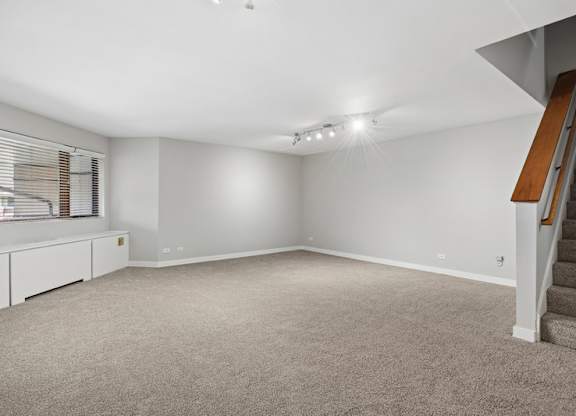 A spacious room with a staircase on the right side.