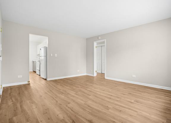 A room with wooden flooring and white walls.