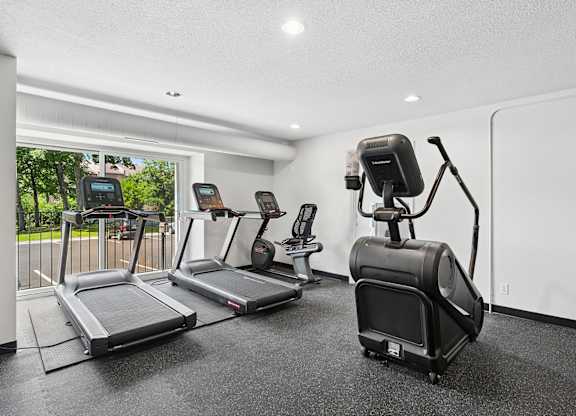 Fitness room with a treadmill, elliptical trainer, and a stationary bike.