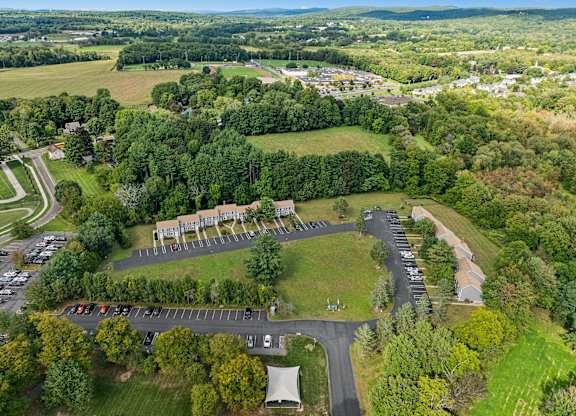 Buildings surrounded by trees and a parking lot.