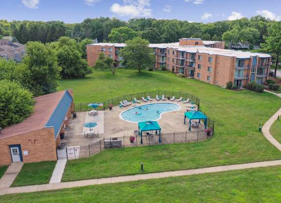 A swimming pool surrounded by a grassy area and apartment buildings.