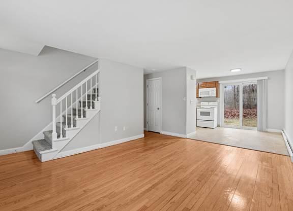 A living room with wooden floors and a staircase.