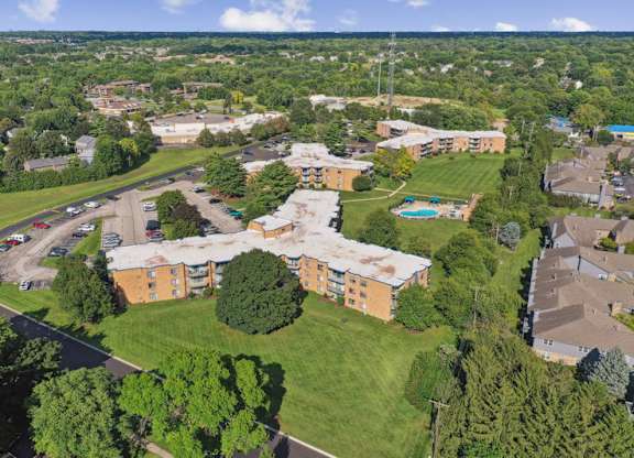 A bird's eye view of a residential area with apartment buildings and a pool.
