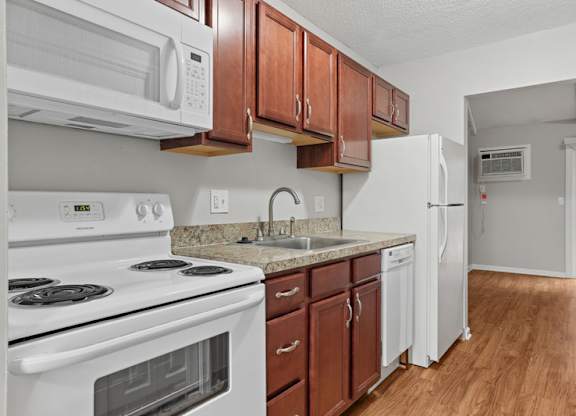 A kitchen with white appliances and brown cabinets.