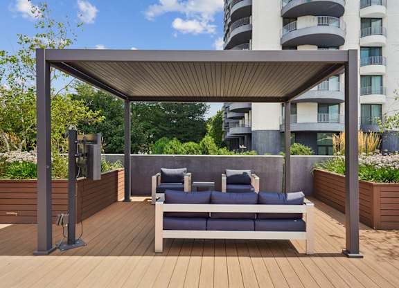A wooden deck with a canopy and two chairs.