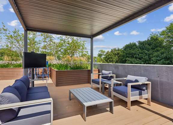 A patio with a grey sofa, blue cushions, and a wooden coffee table.