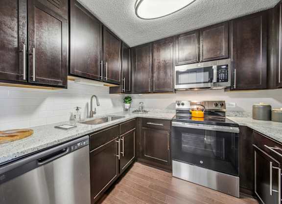 A kitchen with dark brown cabinets and stainless steel appliances.