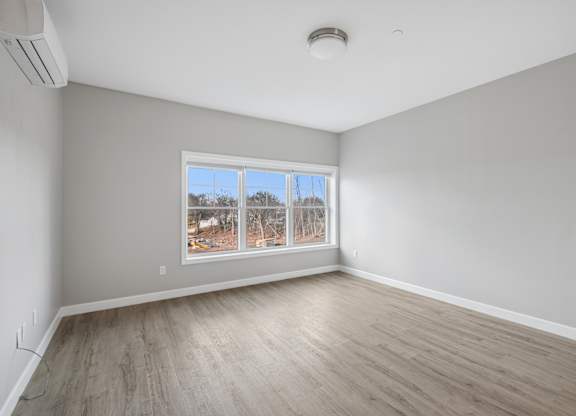 A room with a large window and wooden flooring.