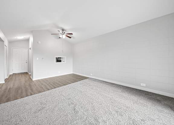 A spacious room with a carpeted floor and a ceiling fan.