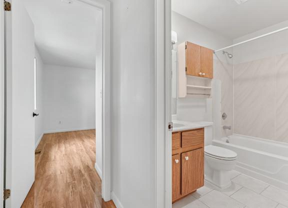 A white bathroom with wooden floors and a white toilet.