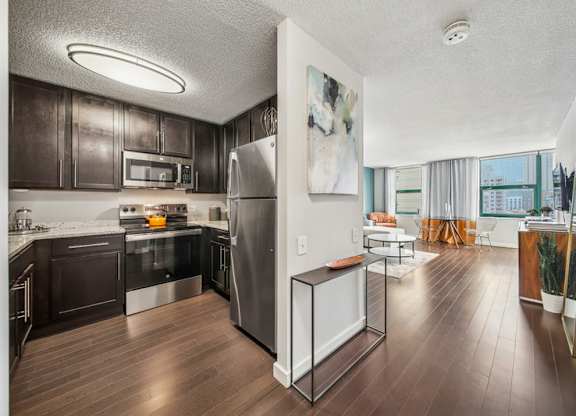 A modern kitchen with dark wood cabinets and stainless steel appliances.