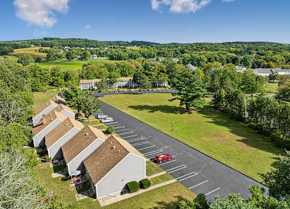 A parking lot is surrounded by a grassy area and a few trees.
