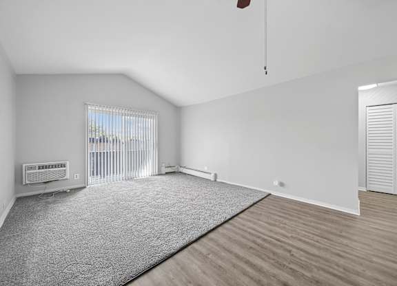 A room with a grey carpet and wooden flooring.