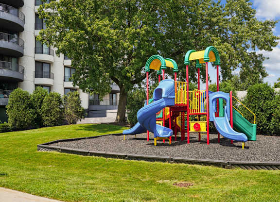 A playground with a blue, yellow and green slide.