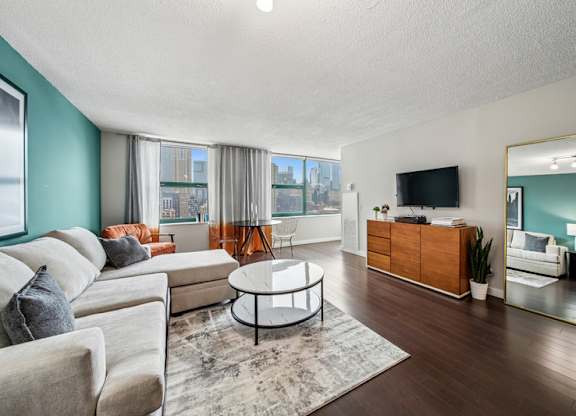 A living room with a white sofa, a coffee table, and a television.