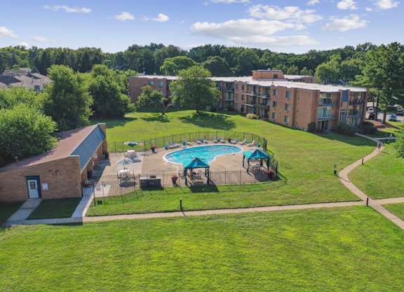 A swimming pool is surrounded by a fence and chairs in a grassy area.