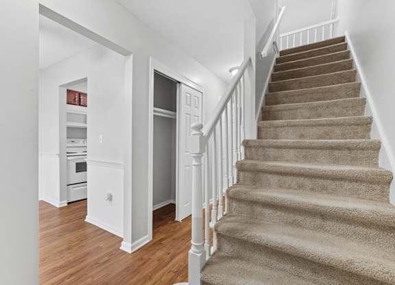 A staircase with carpet and white banister that leads to a second floor.
