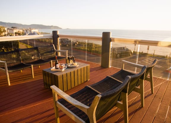 a deck with a table and chairs overlooking the ocean
