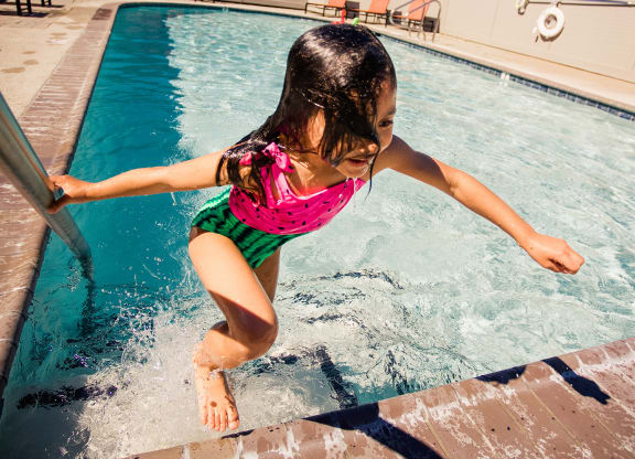 a little girl jumping into a swimming pool
